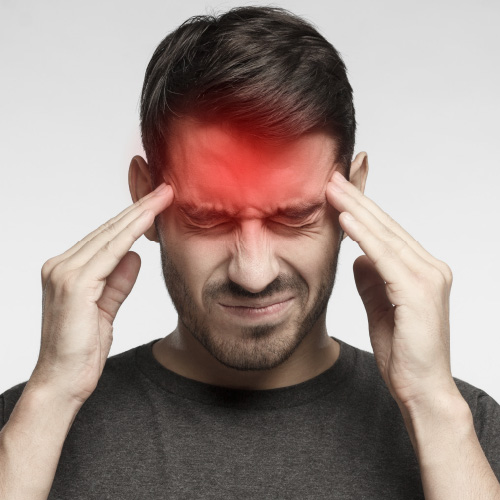 man presses his fingertips to the side of his head to relieve his headache pain