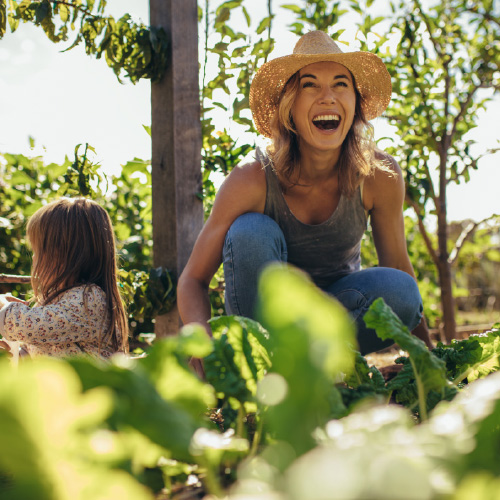 woman and a young girl kneel on the ground to garden