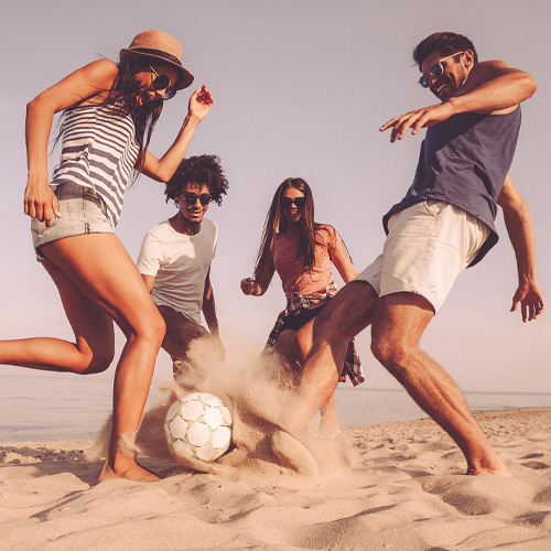 family playing beach soccer and kicking the ball between each other