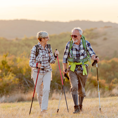 Senior couple hiking with backpacks and walking sticks