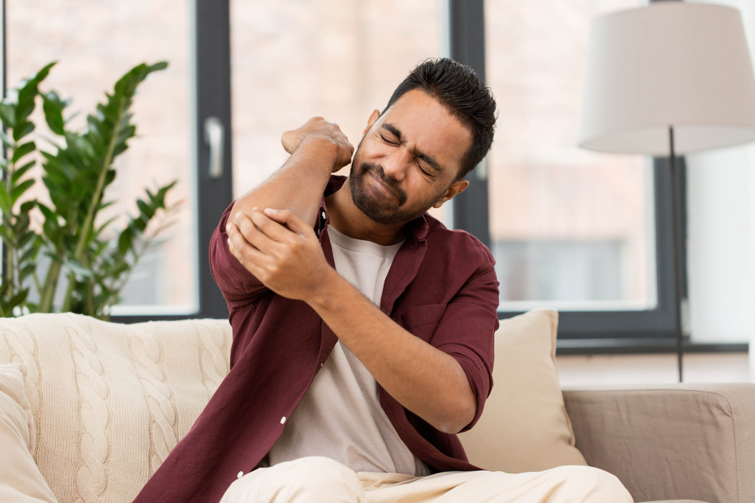 Man reacting to sudden elbow pain and holding his right elbow
