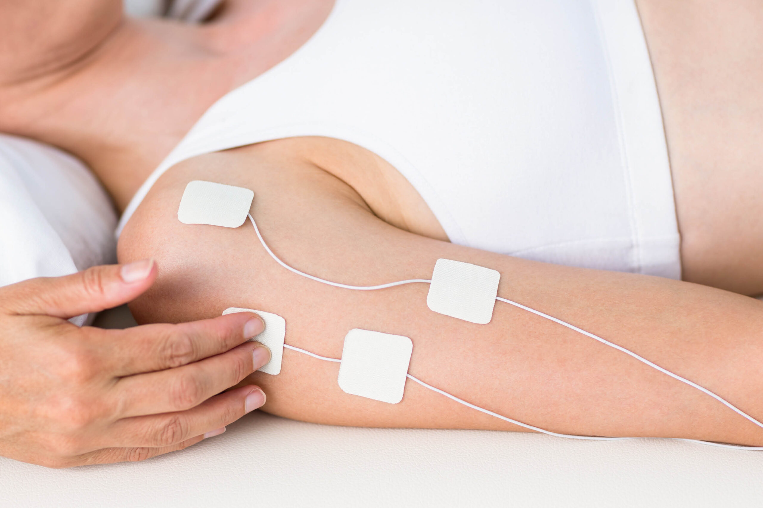 Physical therapist using electrotherapy on patient’s shoulder to improve circulation