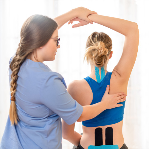 physical therapist guiding patient with kinesio tape through shoulder mobility exercise