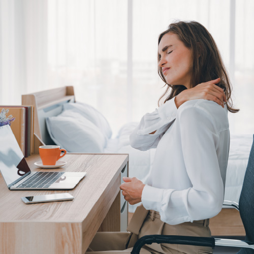 Woman interrupted from working by her joint pain and stopping to massage neck